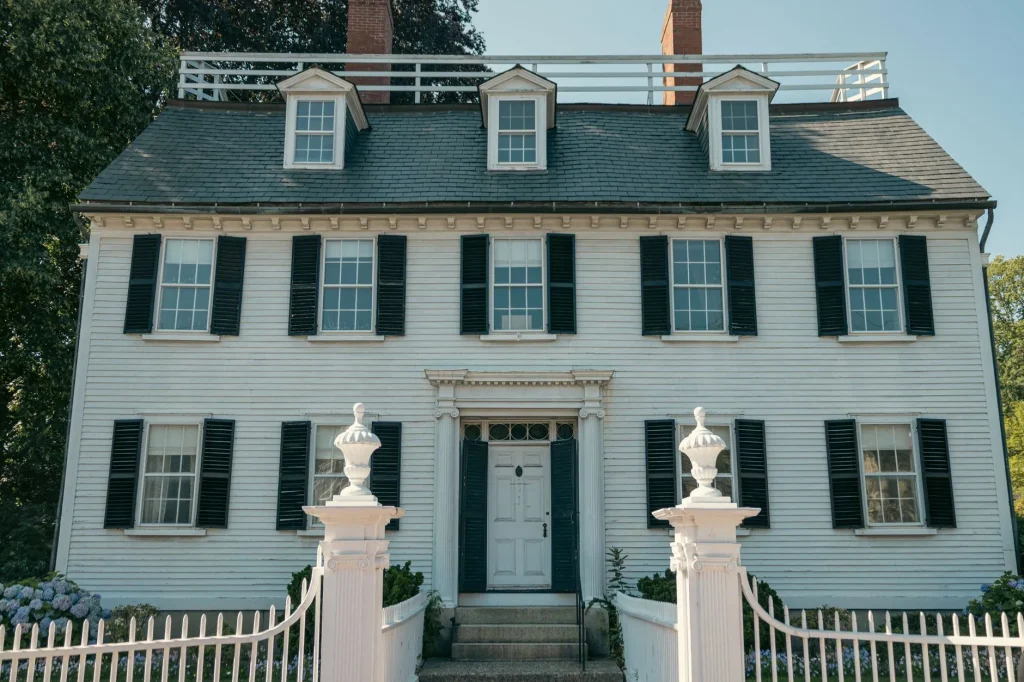 Elegant Colonial-style house with black shutters and white picket fence in Salem, Massachusetts.